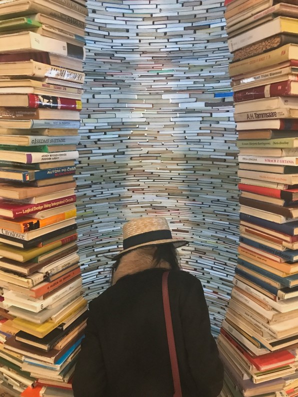 girl in front of tunnel of books in municpal library of prague