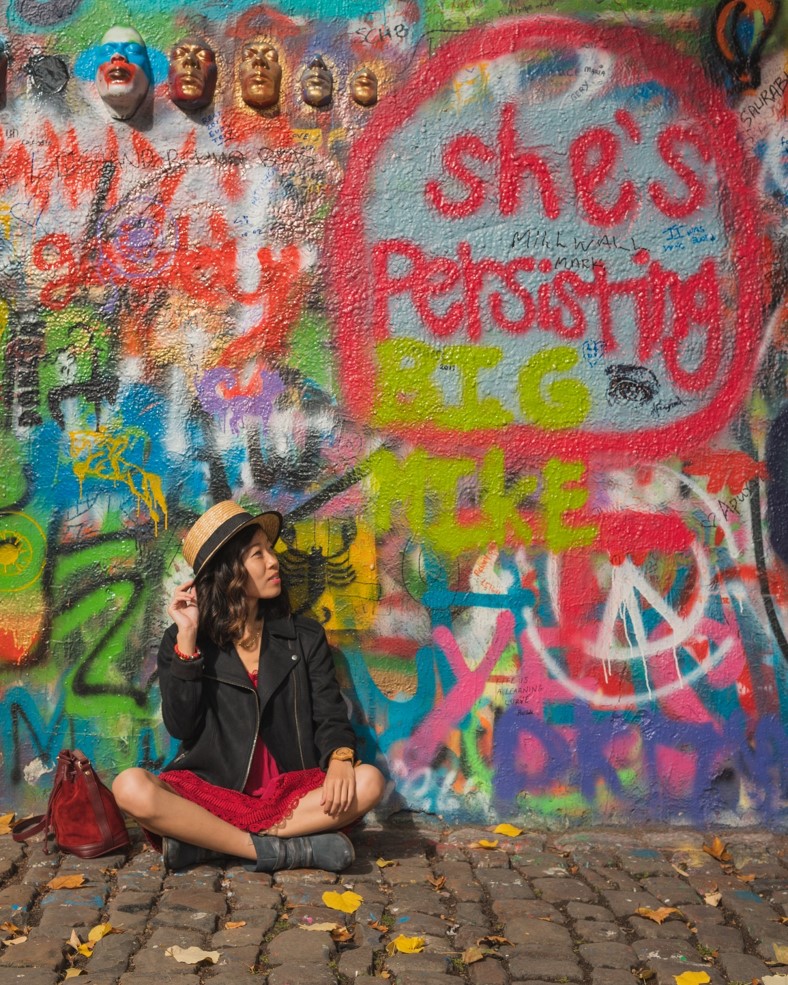 photo of girl in front of the lennon wall artwork in prague