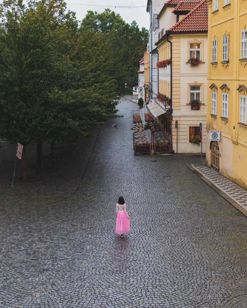 girl wearing a pink dress in the middle of empty cobblestone street