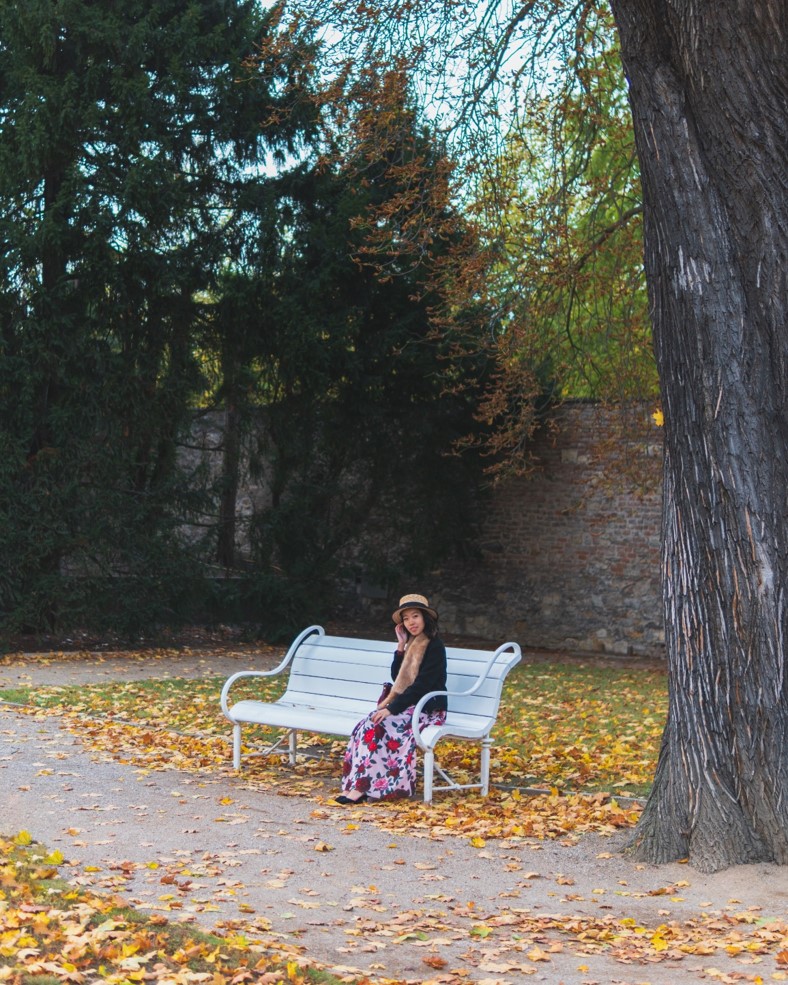 girl sitting on bench with fall colors and trees