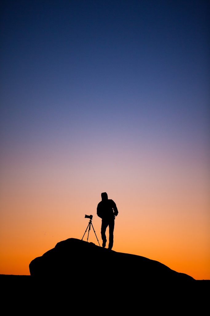 sillhouette of person at sunset taking a photo
