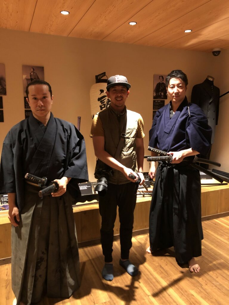 person standing between two people dressed as samurai. the person in the middle is smiling so it seems like its for fun