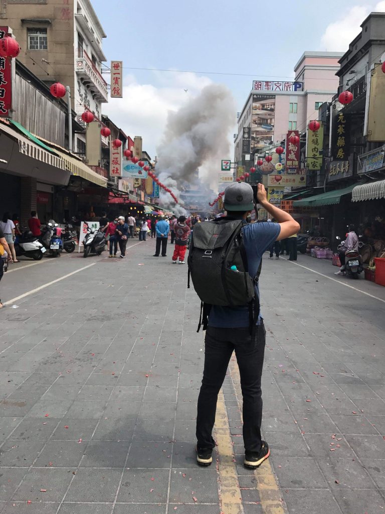 image of person with backpack shooting a camera with smoke in the background