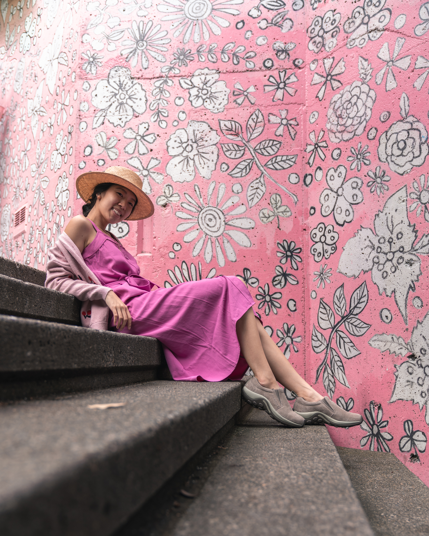 Girl sitting on stairs in front of pink mural