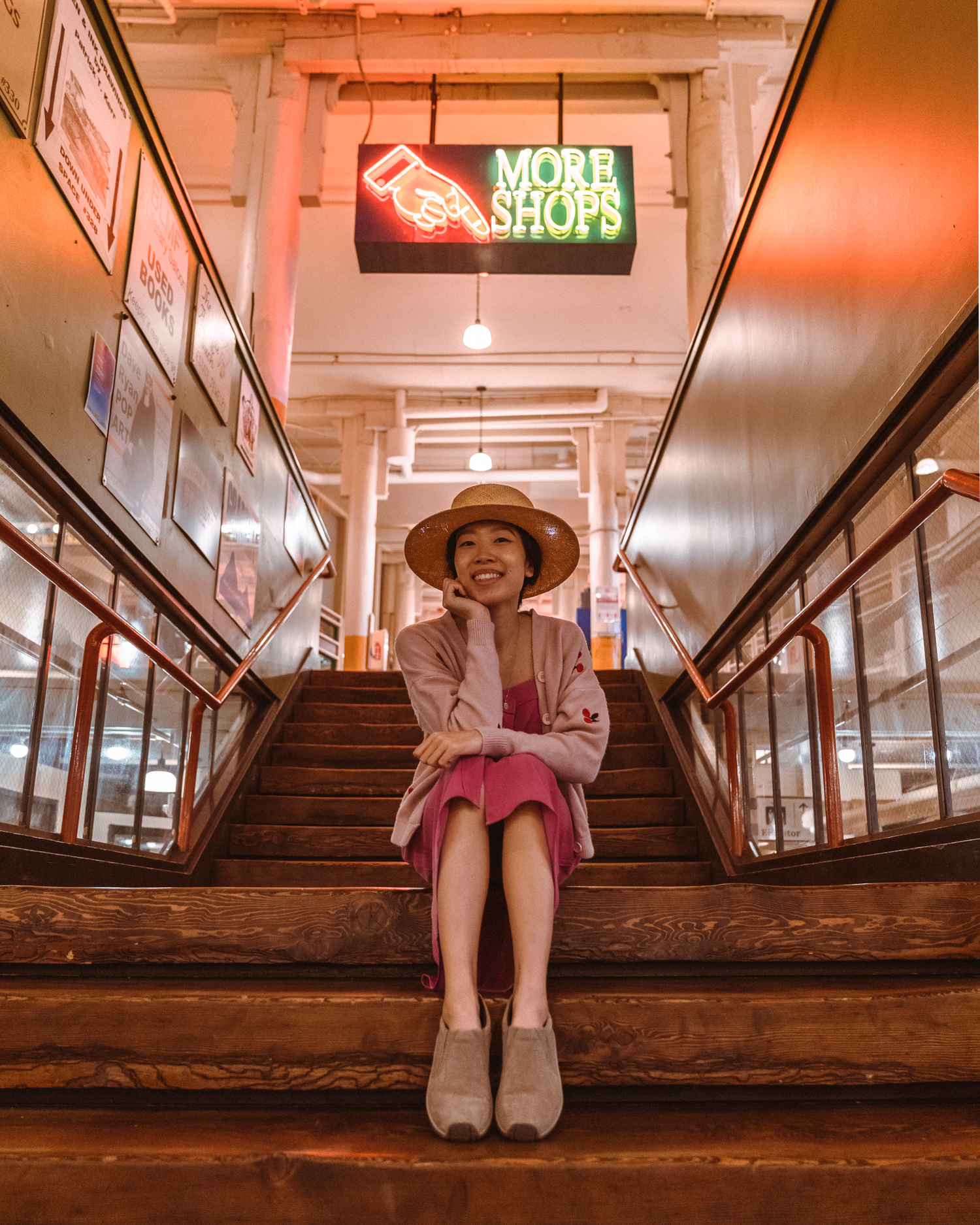 Girl sitting on stairs in front of neon sign