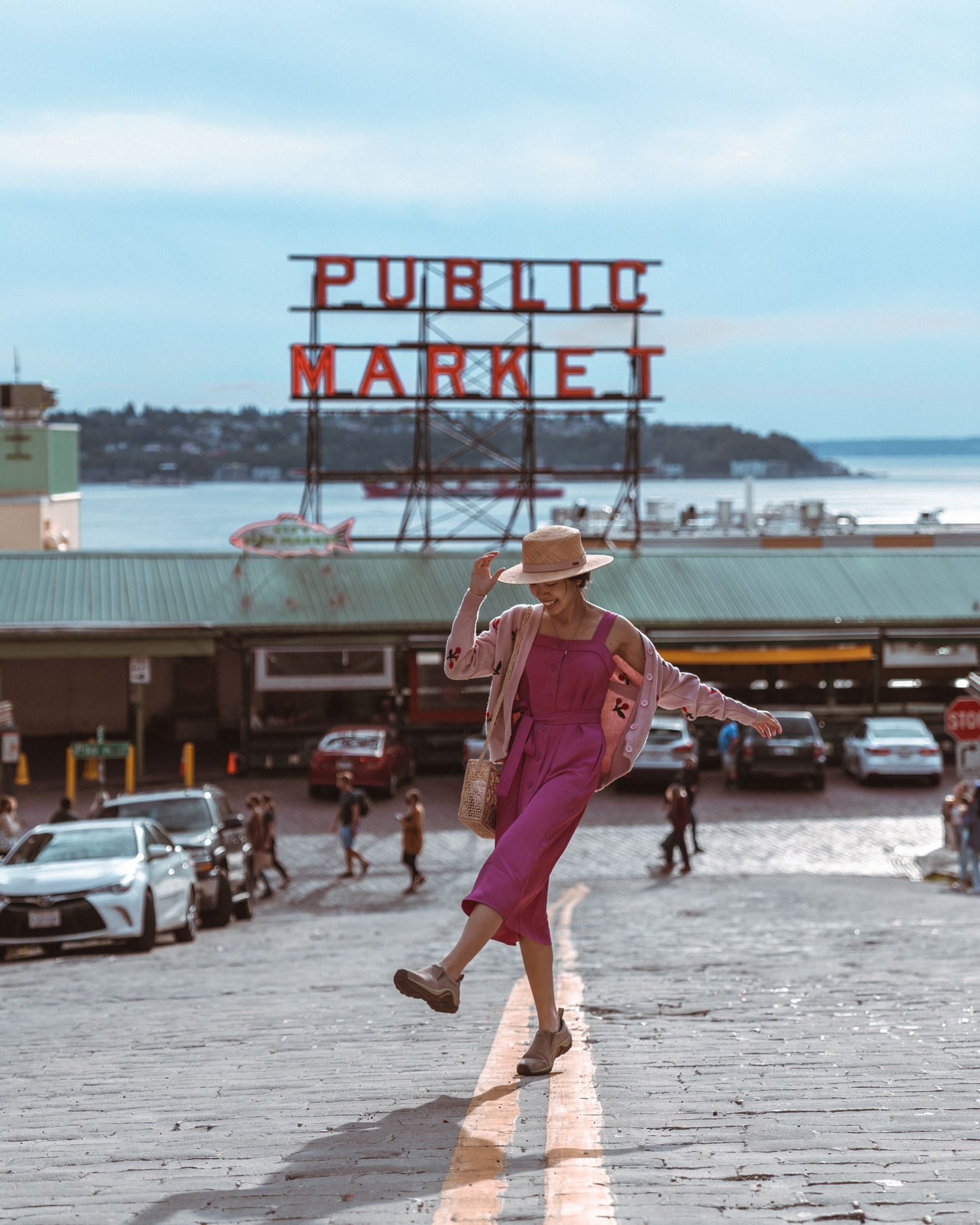 Girl in front of Public Market sign in middle of road at Pike Place Market, Seattle