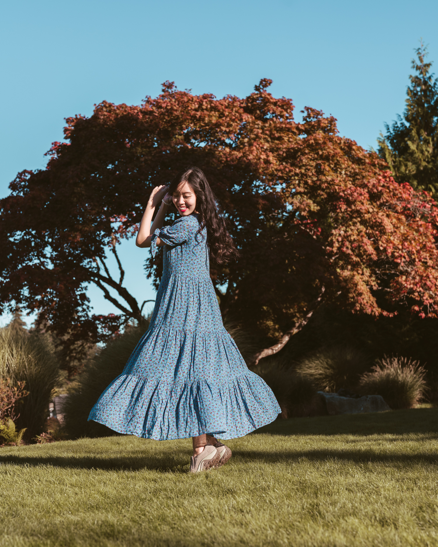 Girl twirling in blue dress in front of autumnal tree