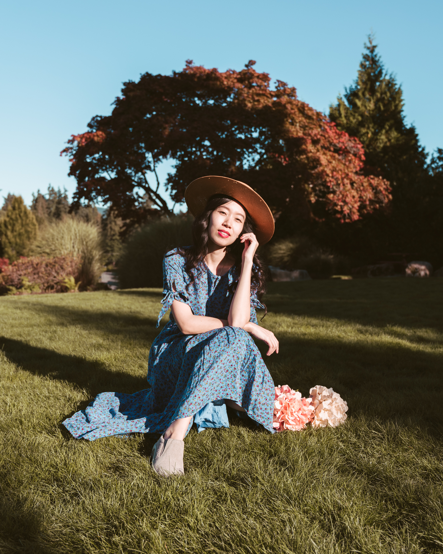 Girl sitting on grass with autumn tree behind her