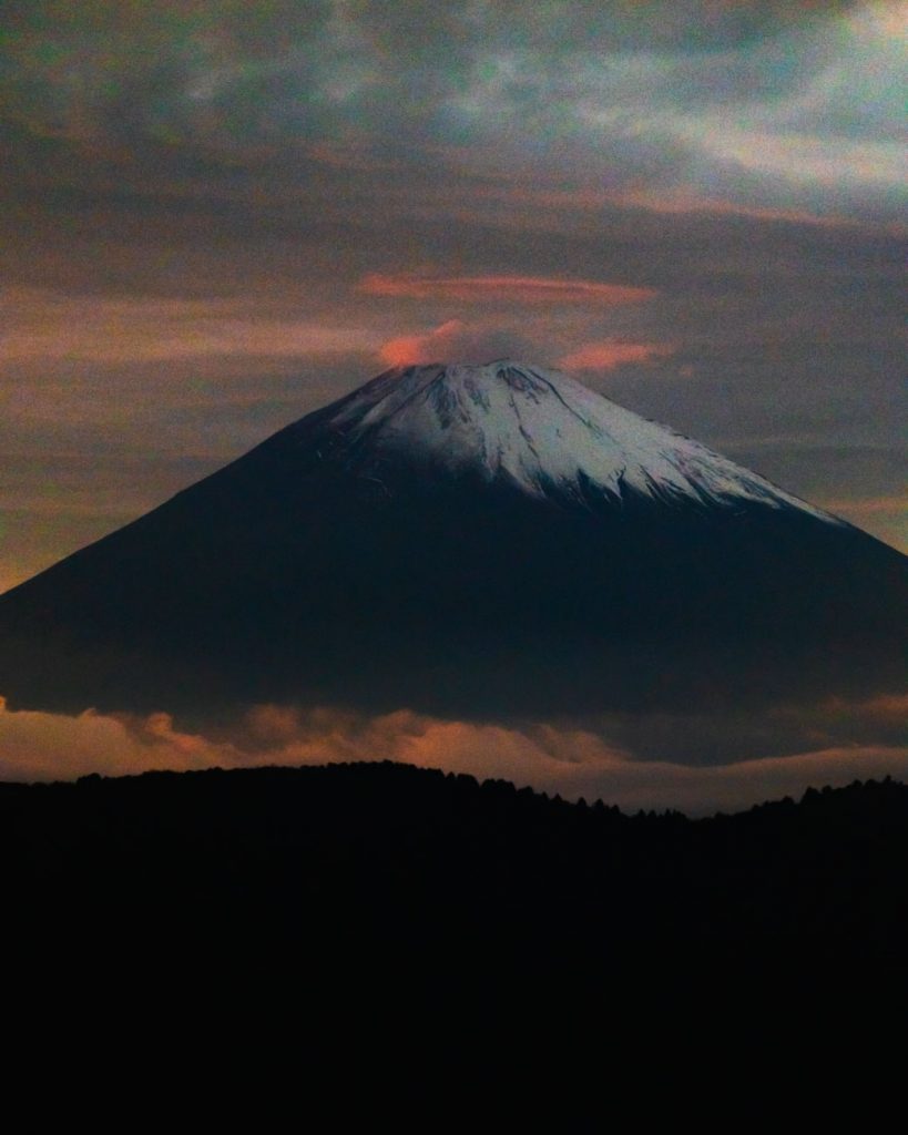 image of mount fuji rising above the clouds with sunset colors