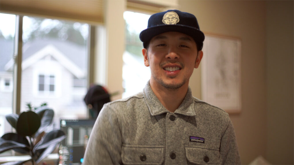 image of a man with a blue hat and gray shirt smiling towards camera