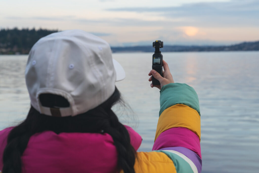 up close image of girl with white hat and colorful jacket using a dji pocket 2 camera