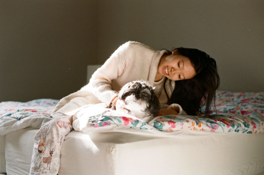 image of girl sitting on bed in sun with shih tzu