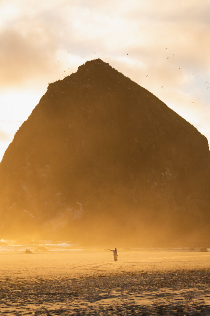 image of a girl in front of cannon beach haystack with orange sunset glow