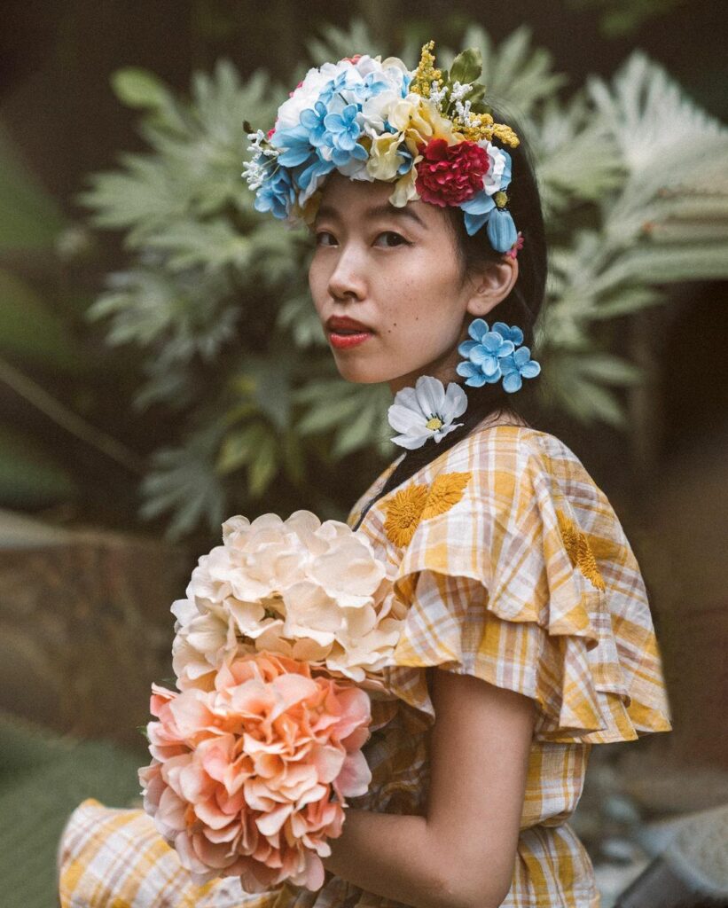 image of a girl with a flower crown in front of green flowers