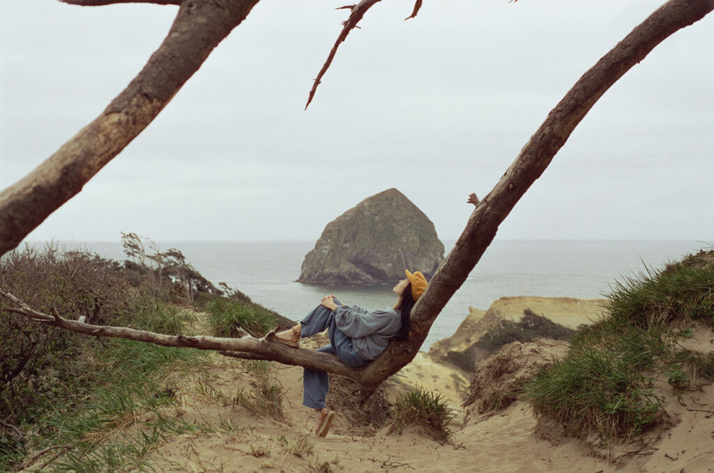 image of girl sitting on branch overlooking oregon coast