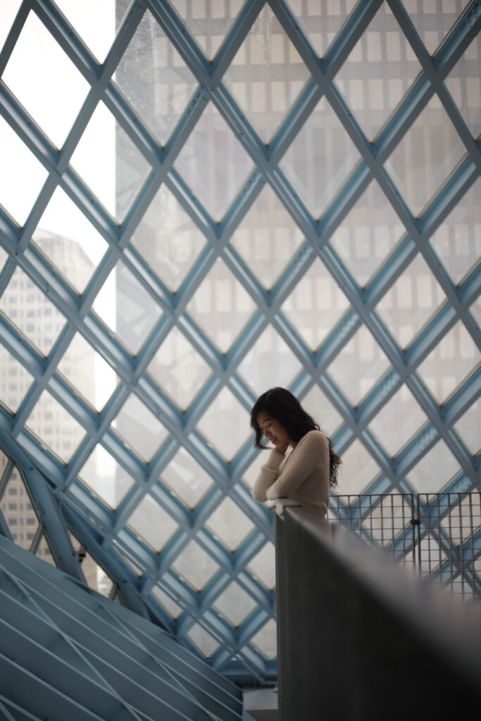 image of girl leaning on rail in front of pattern window